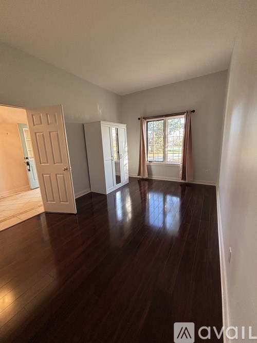 A room with wooden floors and a door on the left side.