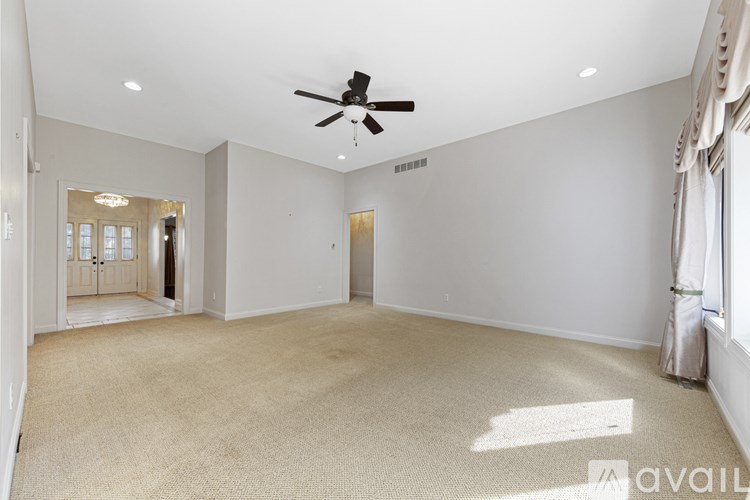 A spacious room with a ceiling fan and carpeted floor.