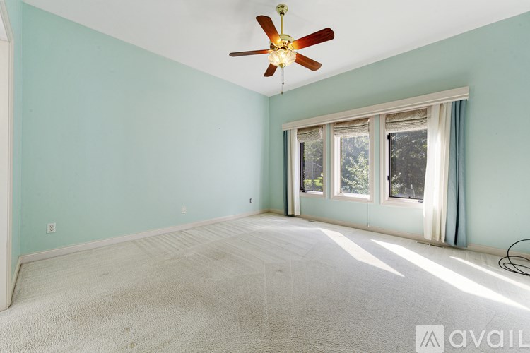 A room with a ceiling fan and a window with curtains.