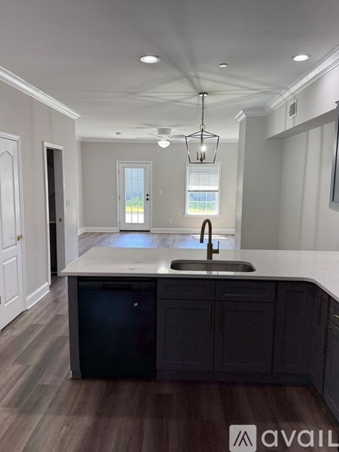 A kitchen with a black fridge and wooden floors.