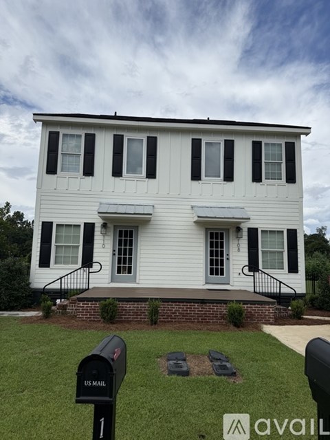 A white house with black shutters and a mailbox in front.