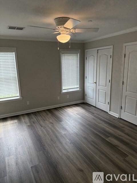A room with a ceiling fan and wooden flooring.
