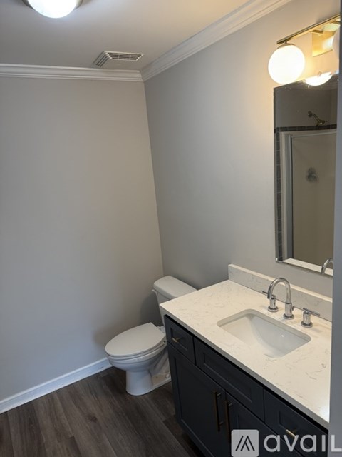 A bathroom with a toilet, sink, and mirror.