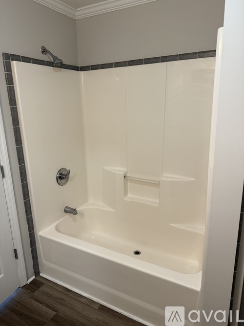 A white bathtub with a grey tile border is in a bathroom.