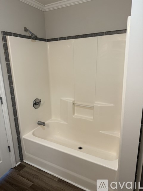 A white bathtub with a grey tile border is in a bathroom.