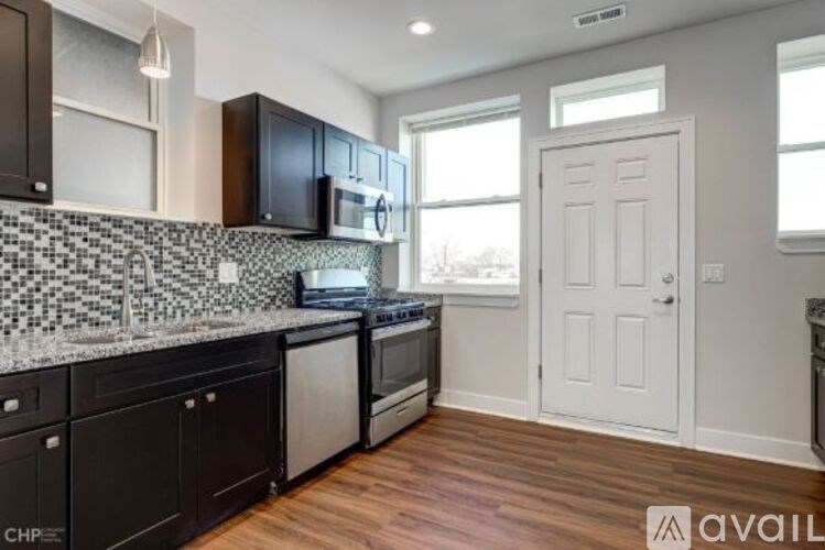 A kitchen with black cabinets and a white door.