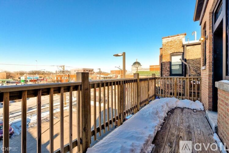 A wooden deck with snow on it and a building in the background.