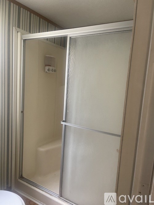 A bathroom with a glass shower door and a white toilet.