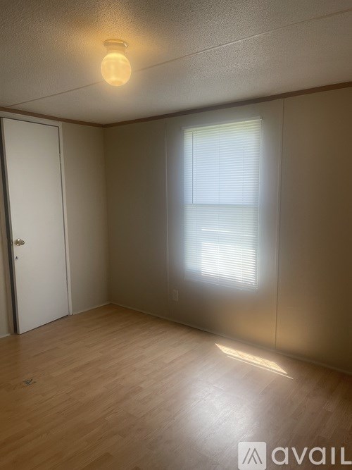 A room with a wooden floor and a window with blinds.