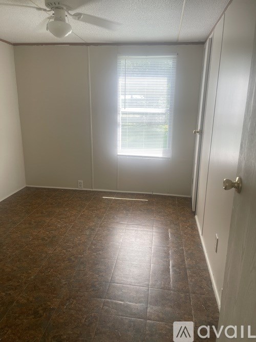 A room with brown tile flooring and a ceiling fan.