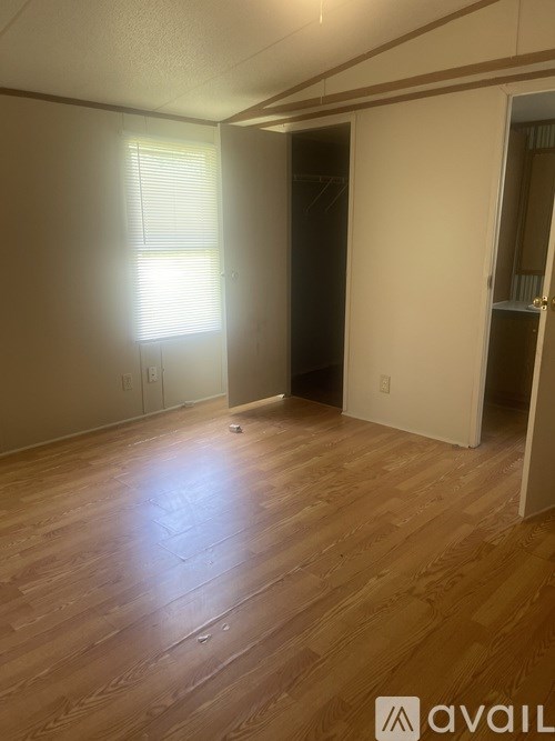 A room with wooden flooring and a window with blinds.