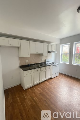 A kitchen with white cabinets and a black countertop.