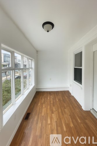 A room with wooden floors and a window overlooking a building.