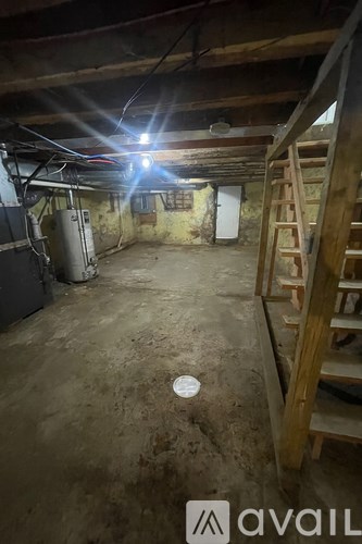 A dirty basement with a ladder and a light on.