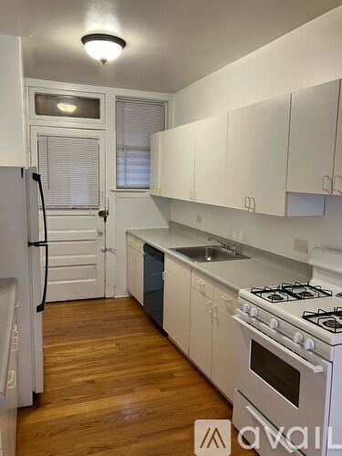 A kitchen with white cabinets and a stove top oven.