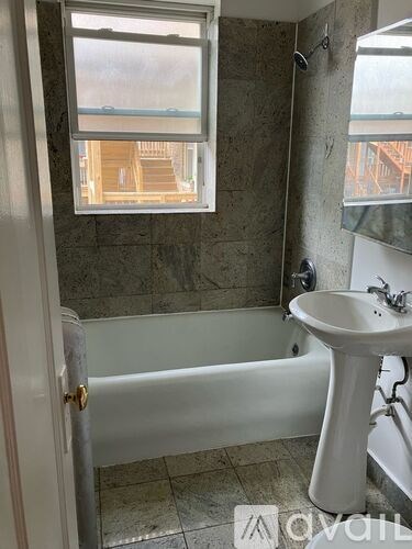 A bathroom with a tub, sink and window.