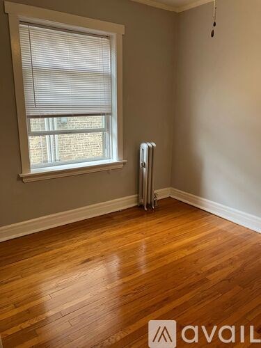 A room with wooden floors and a window with blinds.
