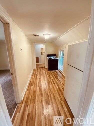 A hallway with wooden floors and white walls.