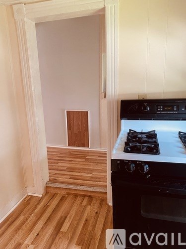 A kitchen with a stove and wooden floors.