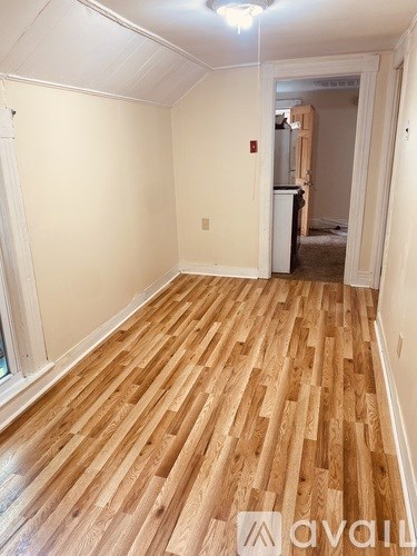 A room with wooden flooring and a doorway leading to another room.