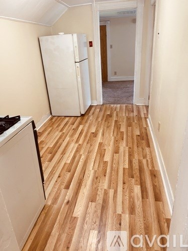 A kitchen with a white fridge and wooden floors.