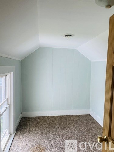 A room with a carpeted floor and a door on the right side.