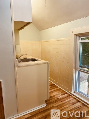 A small bathroom with a window and wooden floors.
