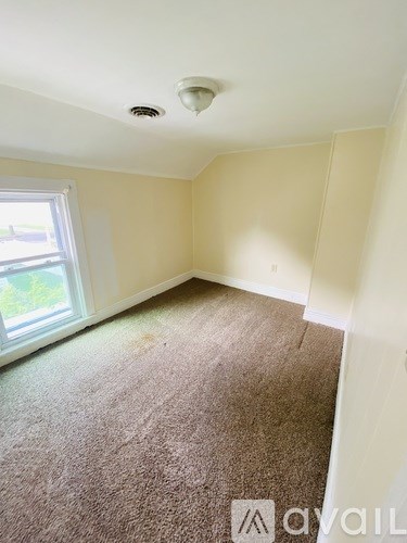 A room with a window and carpeted floor.