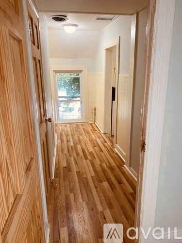 A hallway with wooden floors and white walls.
