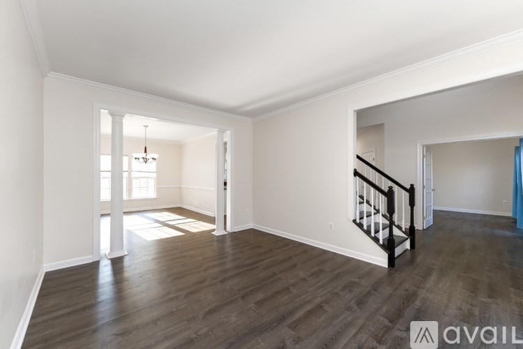 A room with wooden floors and a staircase with a black railing.