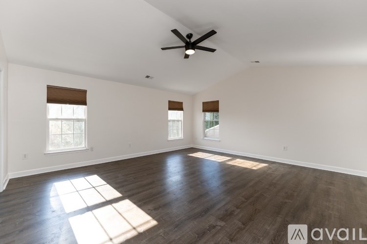 A spacious room with wooden floors and a ceiling fan.