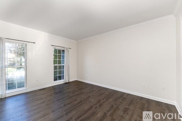 A room with wooden floors and white walls, with a window on the left side.