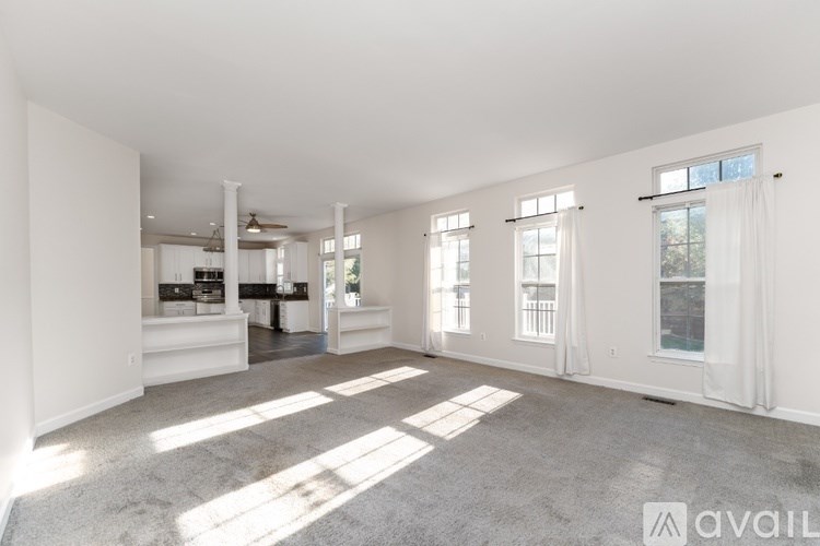 A spacious living room with a carpeted floor and large windows.