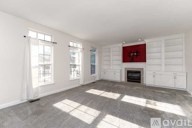 A large, empty room with a fireplace and a carpeted floor.