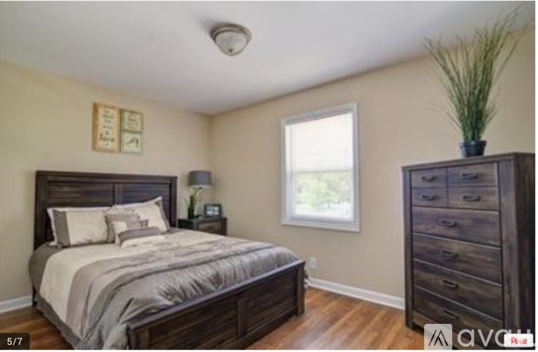 A bedroom with a bed, nightstand, and dresser.