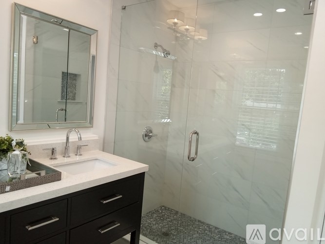 A bathroom with a sink, mirror, and shower.