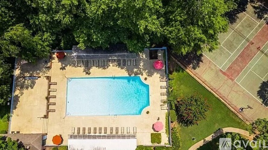 An aerial view of a pool surrounded by trees and a tennis court.
