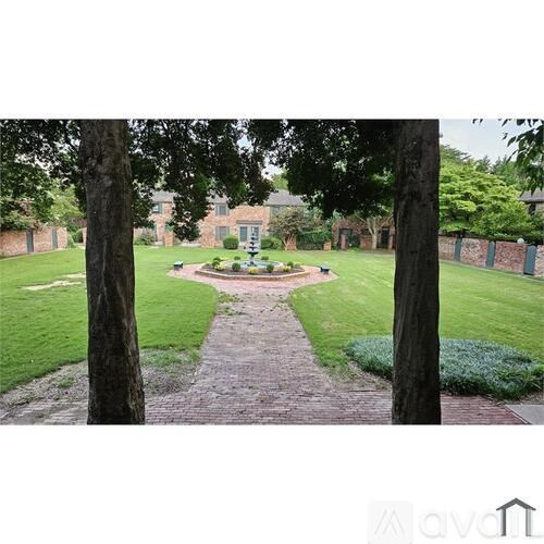 A garden with a brick pathway and a fence in the background.