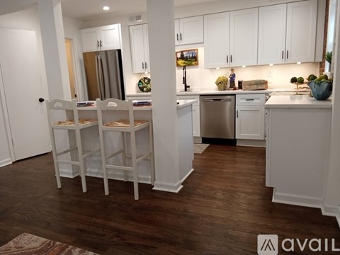 A kitchen with white cabinets and a wooden floor.
