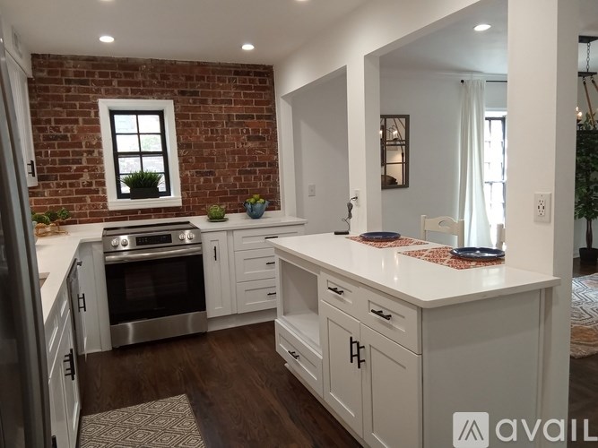 A kitchen with white cabinets and a brick wall.