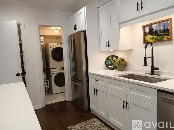 A kitchen with white cabinets and a painting hanging above the sink.