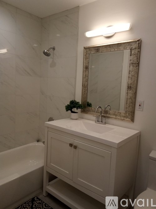 A white bathroom with a marble wall and a white sink.