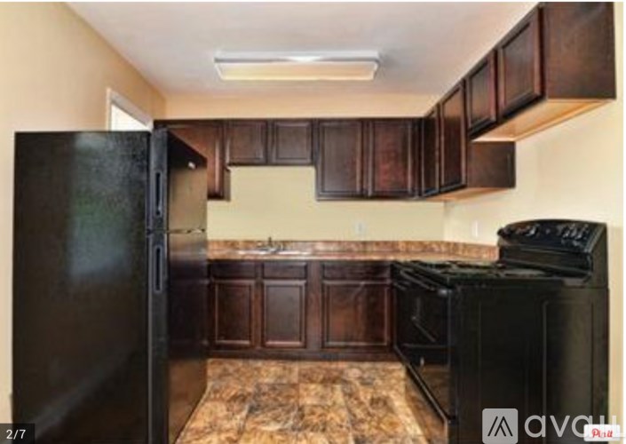 A kitchen with black appliances and brown cabinets.