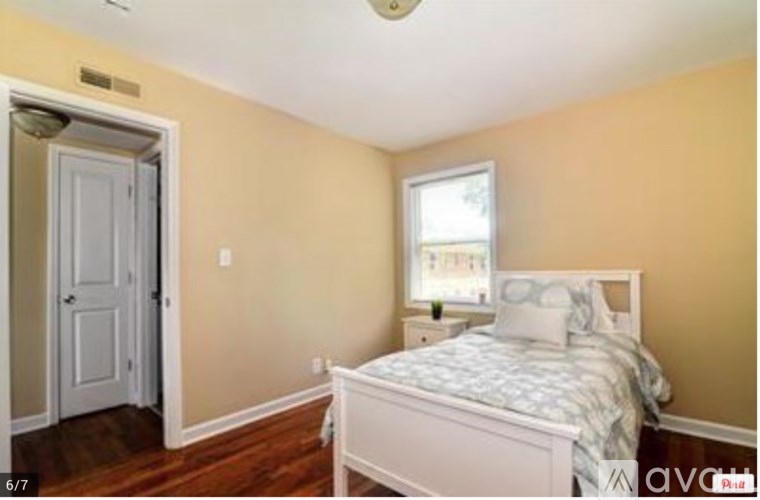 A bedroom with a bed, nightstand, and window.