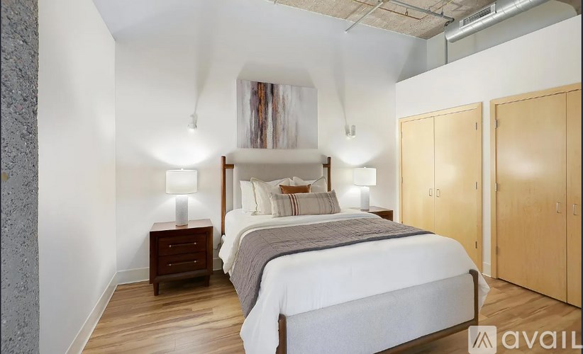 A bedroom with a large bed, two nightstands, and a wooden wardrobe.