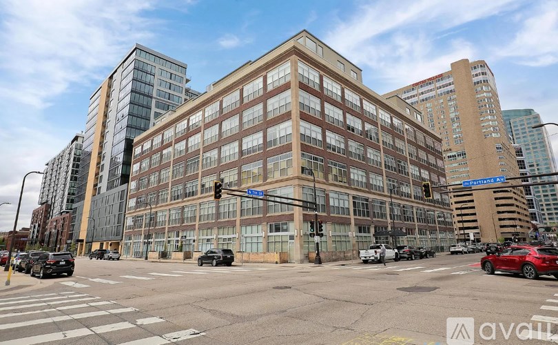 A street view of a city intersection with a large building in the background.