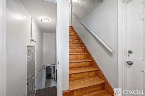 A staircase with a white door on the right and a white wall on the left.
