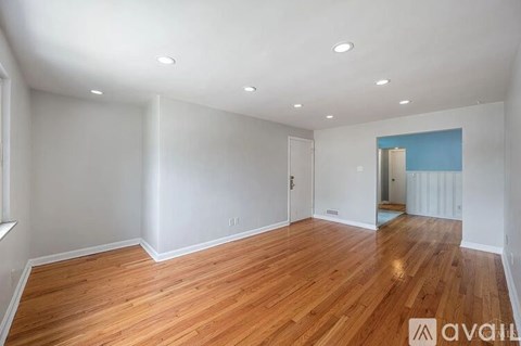 A room with wooden floors and white walls is available for rent.