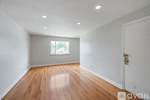 A room with wooden floors and white walls is available for rent.