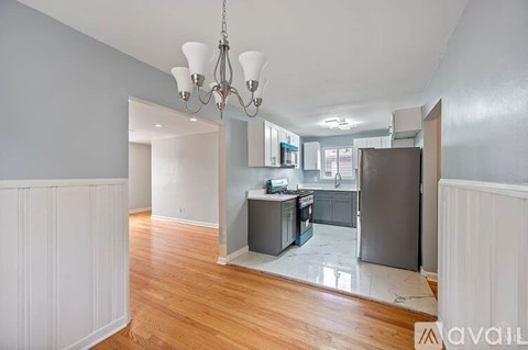 A kitchen with a refrigerator, cabinets, and a chandelier is shown.